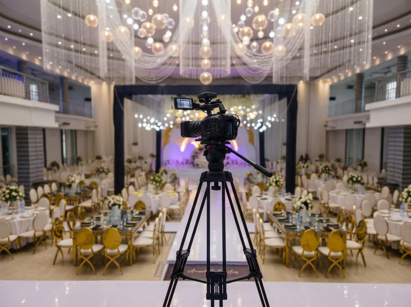 A video camera on a tripod in a decorated event hall